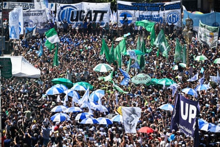 crowd of demonstrators with blue and white umbrellas and green signs