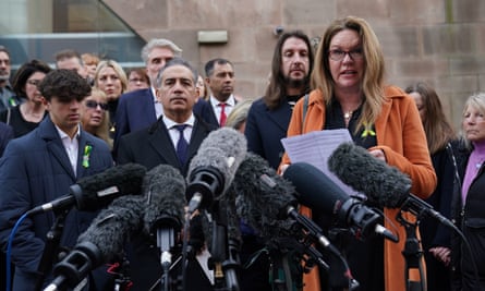 Emma Webber surrounded by families of the victims addresses a row of press microphones 