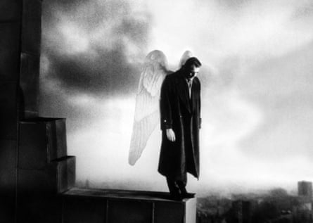 Bruno Ganz, as an angel in an overcoat and wings, looks down over Berlin from a rooftop in Wings of Desire (1987)