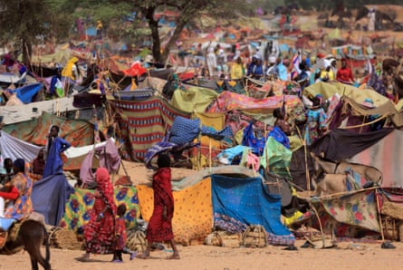 A jumble of tents improvised from cloths and sticks in a desert-like landscape