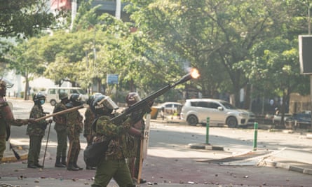 A police officer shoots a teargas canister at protesters