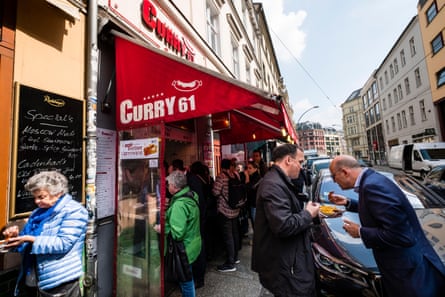 People queueing and eating outside Curry 61 currywurst fast food restaurant in Mitte Berlin Germany.