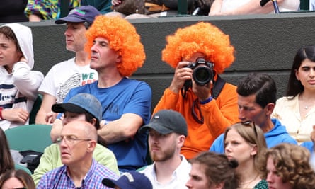 Wimbledon tennis fans wear orange wigs to the match. 