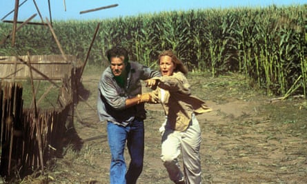 film still of man and woman running with corn field behind them