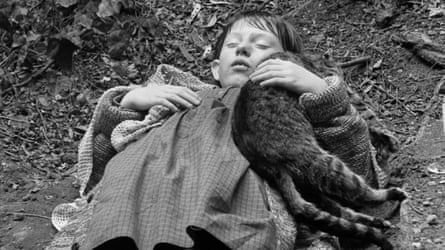 Sátántangó (1994). Close up of a young boy lying on the road clutching a coat and a cat