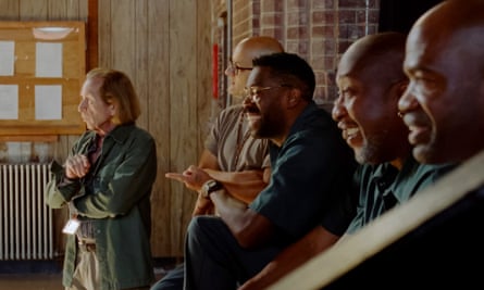 film still of line of men in a room looking at something