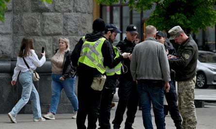 A Ukrainian serviceman and police check the documents of a man in Kyiv