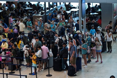 A mass of people with suitcases seen from a second interior story.