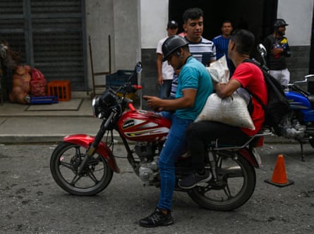 A man carries a sack of coffee on the back of a motorbike