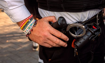 Closeup of the hands of a police officer or security guard, wearing friendship bracelets