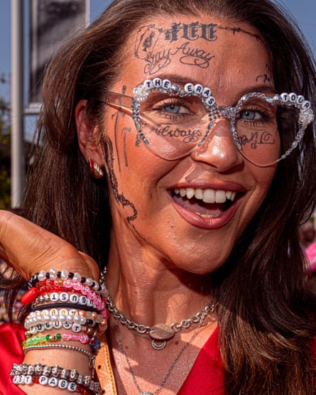 A woman with a tattooed face, heart sunglasses and a wrist full of friendship bracelets