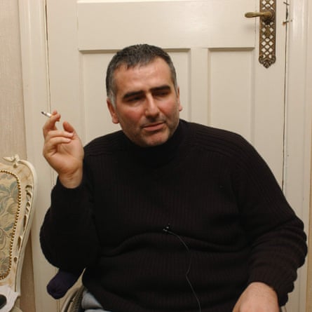 Abdullah Baybasin, sitting in a wheelchair in front of a closed door and smoking a cigarette