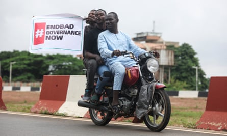 Demonstrators carry a placard as they ride on a motorcycle during the End Bad Governance protest in Abuja on 1 August.