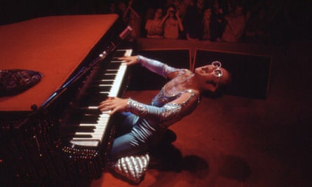 man in a blue sparkly outfit placing the piano exhuberantly