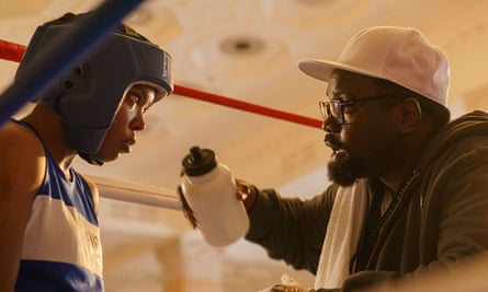 film still of man offering water bottle to female boxer