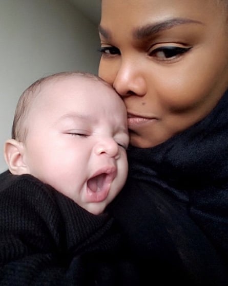 Portrait of Janet Jackson kissing her baby son’s head, who is yawning.