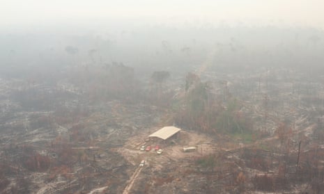 aerial view of a large barn in a burned out landscape obscured by smoke