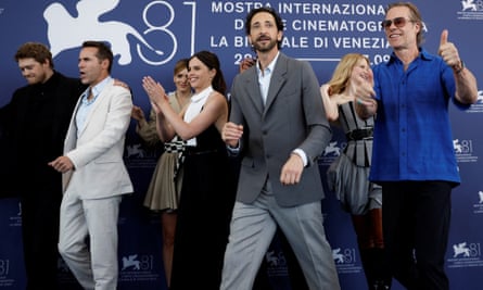 Cast members walk past a blue Venice film festival backdrop at a photo call