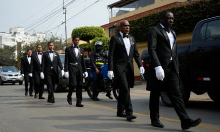 Funeral workers walk outside the house of the late former president.