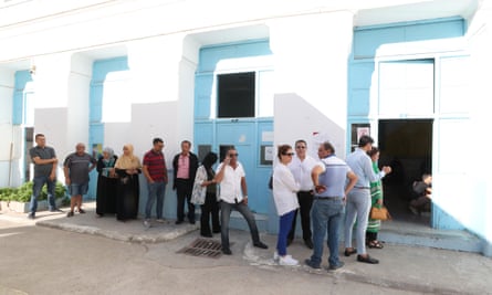 People stand in a queue outside a polling station.