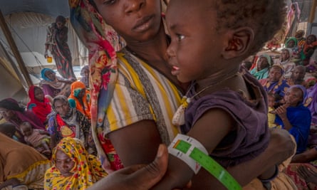 A woman holds her child as the child receives medical treatment