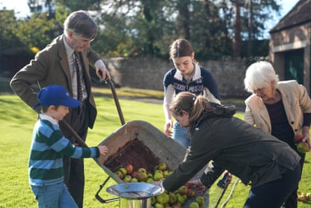 Rees-Mogg and family pour apples into a cider press outside in their large garden.