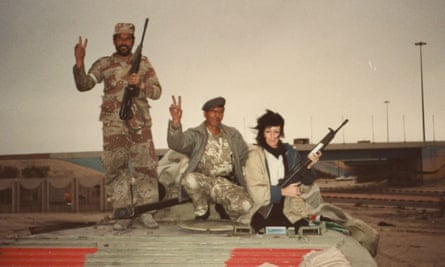 She sits with soldiers in the Gulf, holding a machine gun