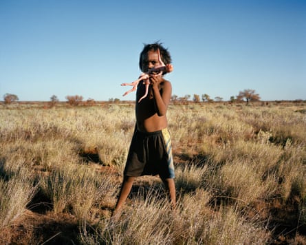 A child holds an action figure in an empty landscape