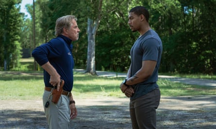 Two men face each other in park, the one on the left reaching for a gun at his hip