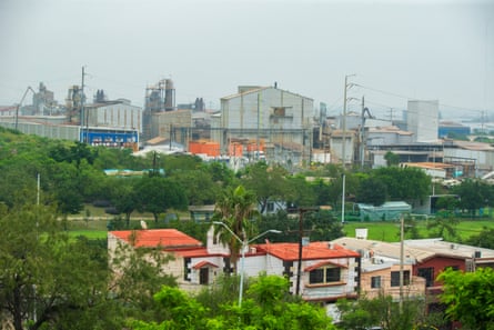 A residential community sits in the shadow of a large industrial facility.