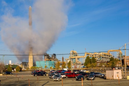 A large industrial facility with plumes of smoke rising over it.