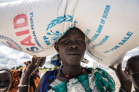 A black woman carrying a sack of food with USAid written on it