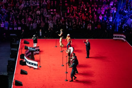 people on a bright red stage - trump dancing behind group of singers