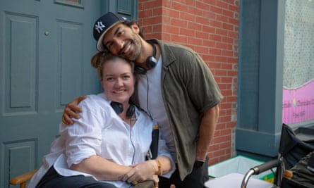 a man wearing a baseball cap puts his arm around a woman sitting down