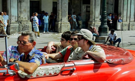 Five men – two upfront, Sean Moore, James Dean Bradfield and Nicky Wire from Manic Street Preachers in the back – in a convertible car with the top down.