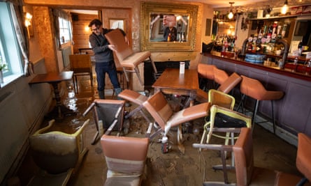 Cimi Kazazi moving one of the tumbled chairs on the ground floor of the pub, which has a layer of mud on the ground