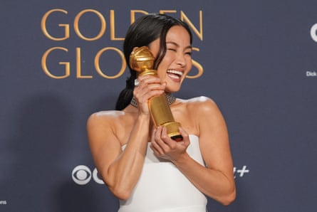 woman holds golden globe in front of sign saying ‘golden globes’