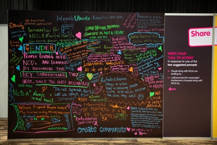 A black wall with positive health messages written on it in neon colours