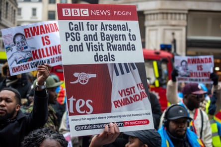 A group of people holding placards saying ‘Rwanda is killing’ and ‘Call for Arsenal, PSG and Bayern to end Visit Rwanda deals’