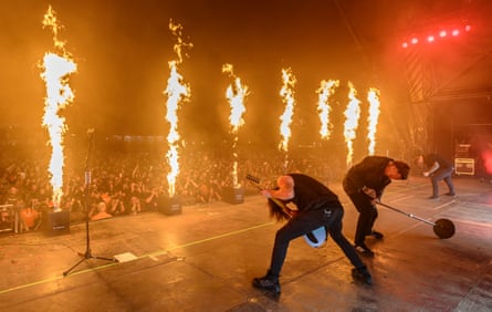 Architects playing to a large crowd in the evening, with flamethrowers shooting fire into the sky