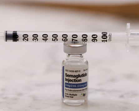 A vial of drugs with a syringe laid across its lid