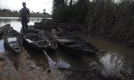 A man stands on fishing canoes surrounded by polluted water in the Niger Delta.