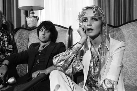 Twiggy and Justin de Villenueve sitting in separate chair, him looking at her from behind