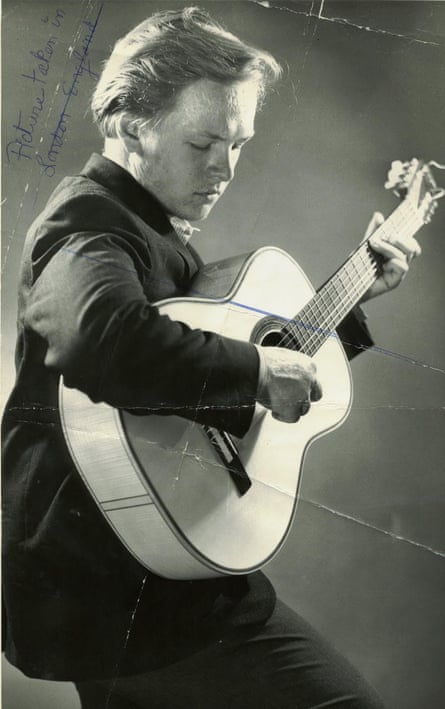 black-and-white photo of person wearing black, playing a guitar