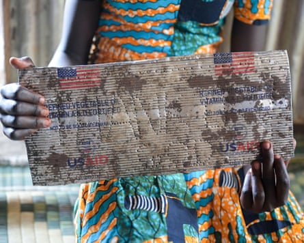An African woman holds a piece of tin with US flags printed on it
