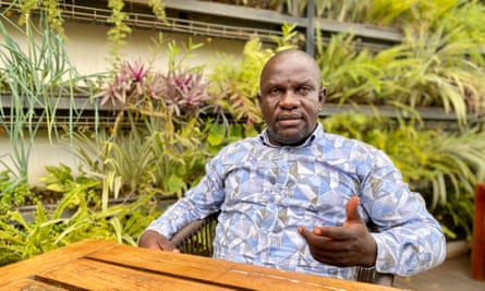 Paul Mwiru gestures as he speaks while seated at a table